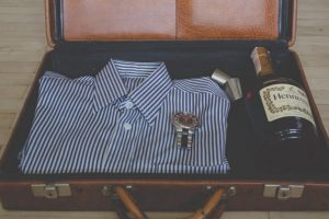 En skjorta klocka och Cognac nedpackad i en resväska